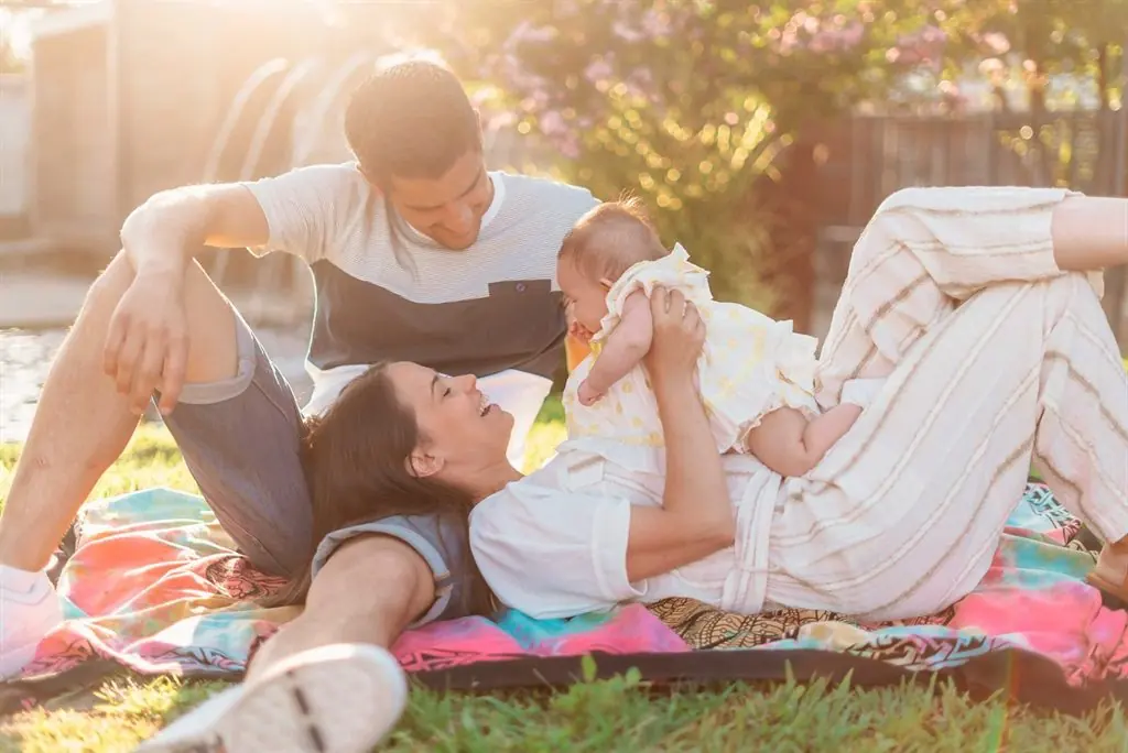 A family on a blanket on the lawn at sunset, bathed in golden light