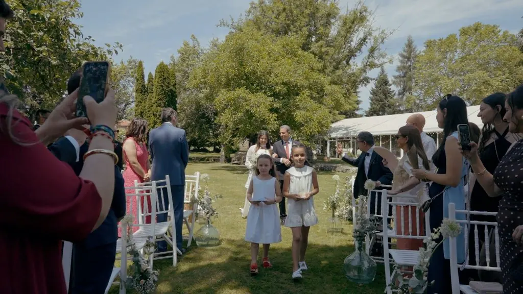 Two girls walk down the ceremony aisle between white chairs