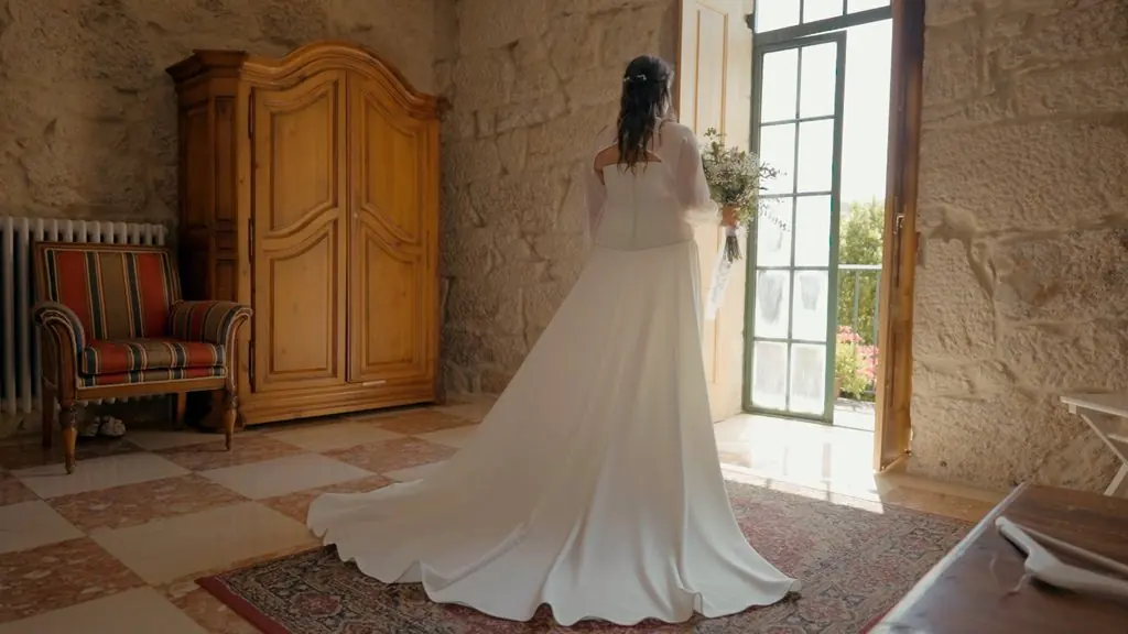 The bride seen from behind by an open door, her train spread across the floor