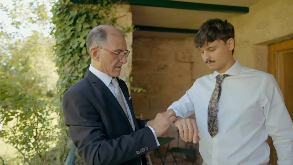 A father helps the groom with his shirt cuff before the ceremony