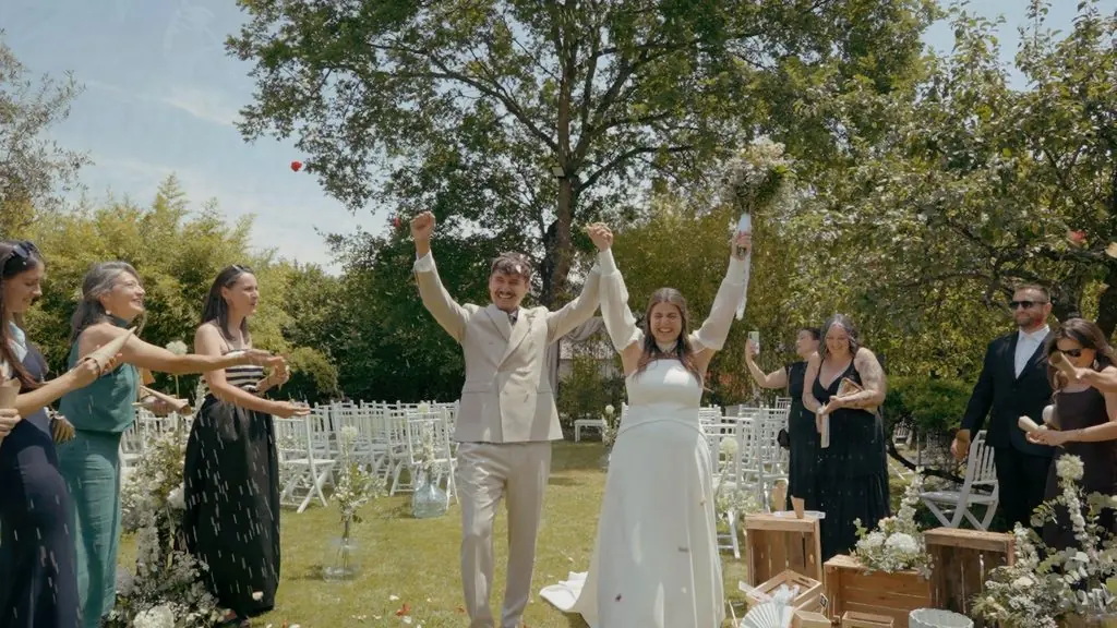 The newlyweds raise their arms among their guests in the ceremony aisle