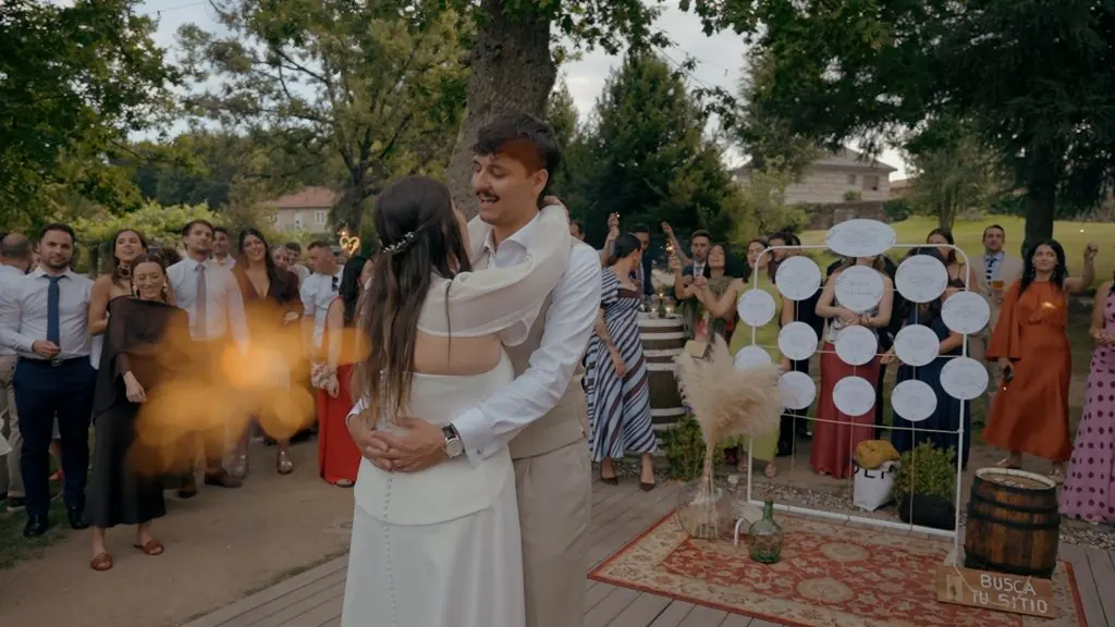 The couple embrace before their guests, a puff of colored smoke beside them