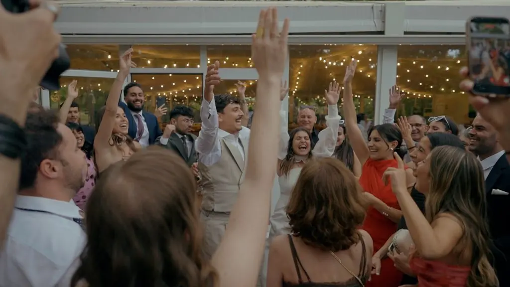 Guests raise their arms and dance beneath string lights