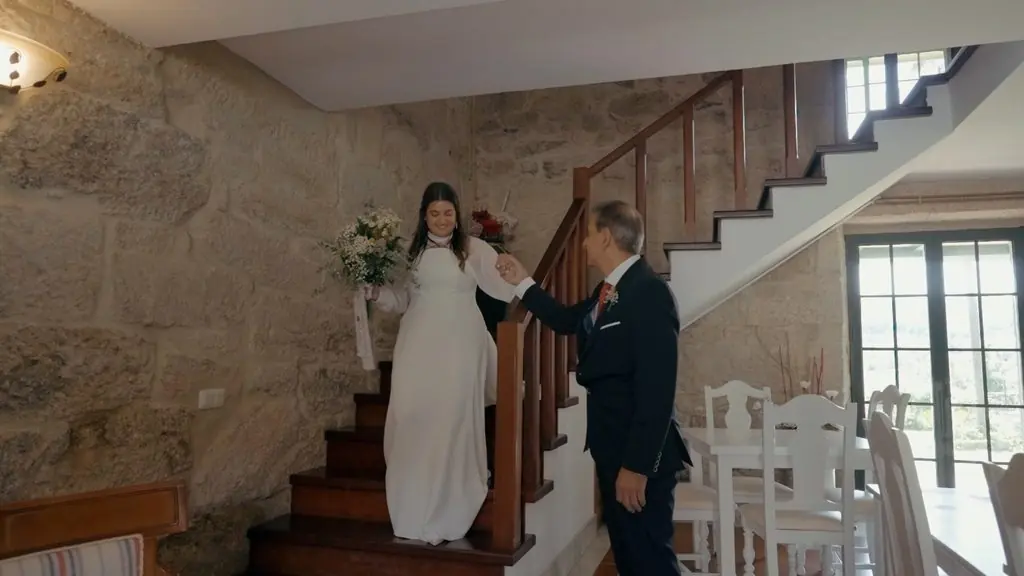The bride descends a stone staircase, hand in hand with a man in a suit