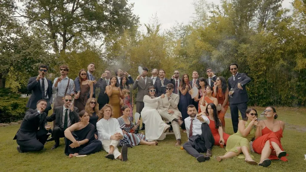 The couple and their guests pose seated and standing on the lawn